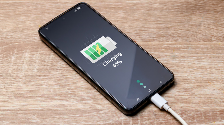 A phone charging on a wooden surface