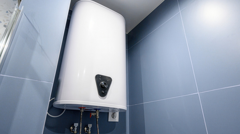A white electric water heater mounted on a tiled wall