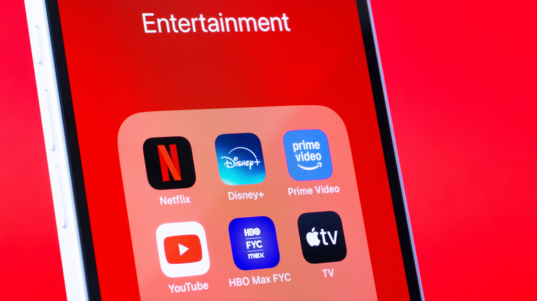 A bunch of entertainment apps in the folder of a smartphone, which is on a red background