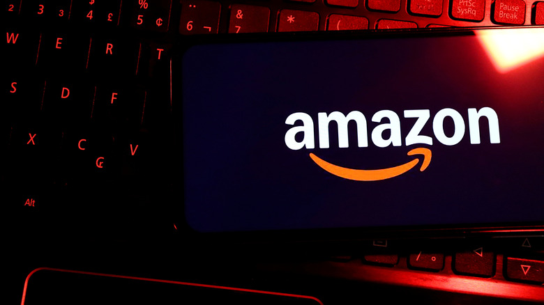 The Amazon logo on a smartphone, placed on a keyboard that's bathed in red light