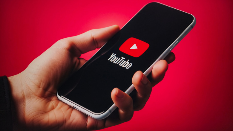 The YouTube logo on a smartphone in front of a red background