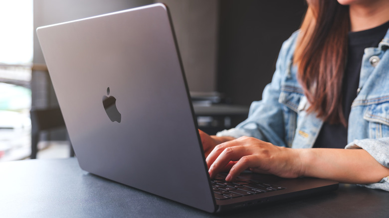 Person using a MacBook to install free and open source apps.