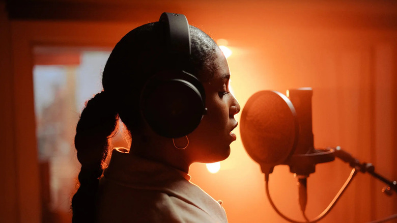 A person singing in the studio while wearing the Beyerdynamic DT 700 Pro X headphones