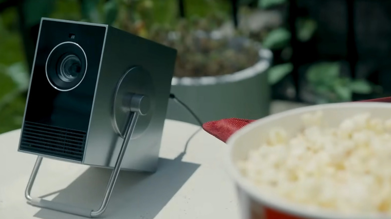 LG CineBeam Q on a garden table next to popcorn