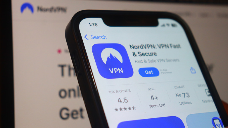An iPhone showing NordVPN on the App Store in front of a laptop