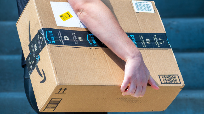 Person carrying a brown Amazon delivery box