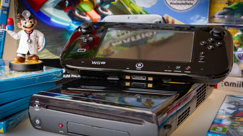 The Wii U and its gamepad placed on a table full of games and a Dr. Mario amiibo