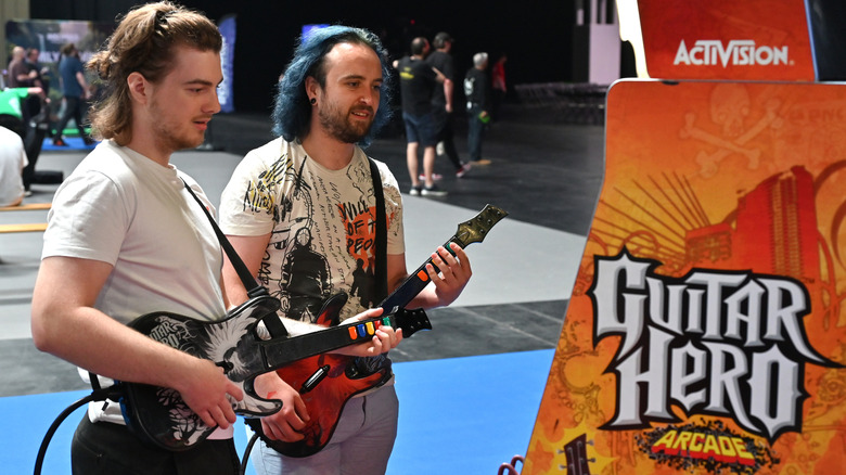 Two people playing Guitar Hero while holding special guitar-shaped controllers