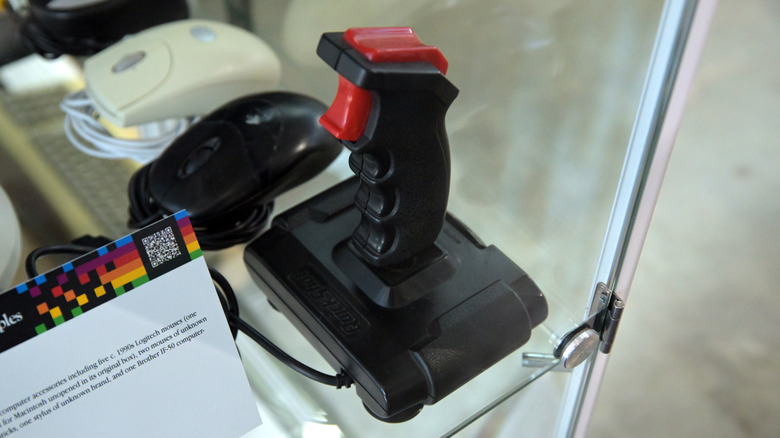 A retro joystick on display inside a glass case