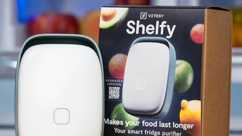 The Shelfy from Vitesy next to its packaging with a blurry background of fruit; the words "Makes your food last longer" appear on the box