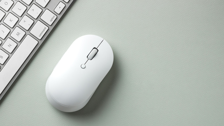White mouse with middle button next to keyboard