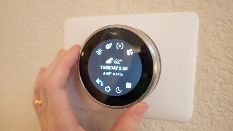 Close-up of hand accessing advanced scheduling functions on a Nest Learning Thermostat