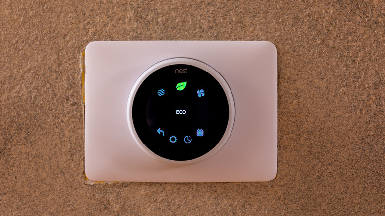 Nest Learning thermostat on the wall displaying operation menu with selected ECO mode