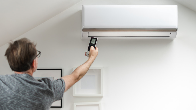 A man setting the temperature in the air conditioning