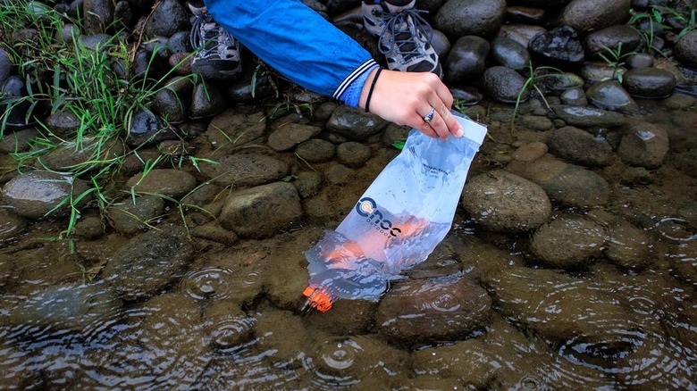 Person using Vecto collection bag on a shallow stream