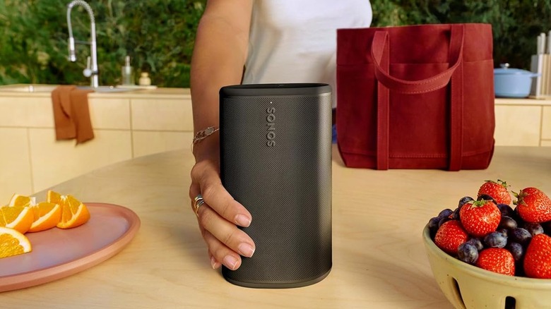 A person placing the Sonos Play on a kitchen countertop.