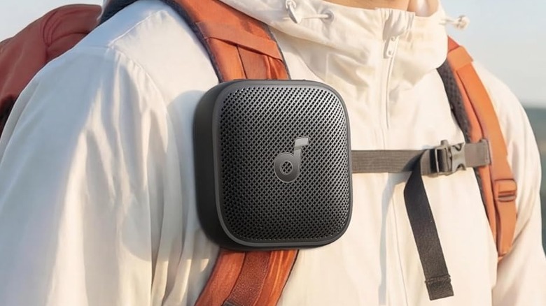 The Soundcore Boom Go 3i attached to the straps of a person's backpack.