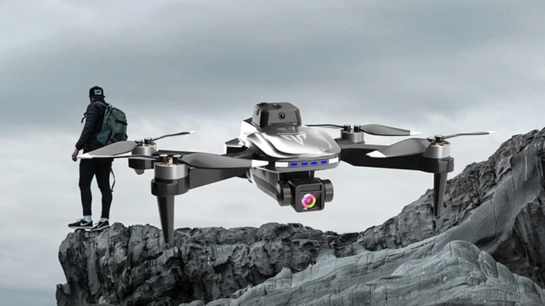 TizzyToy BL01 flying close to a mountain with a man behind standing on the cliff.