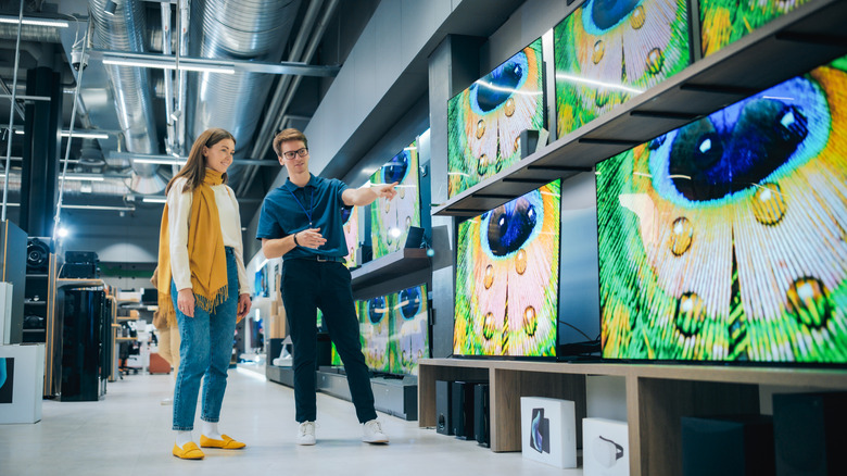 A young woman having a conversation with an associate in a TV store