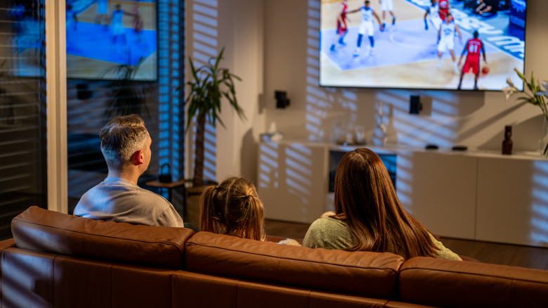 A family relaxing on a sofa and watching basketball match