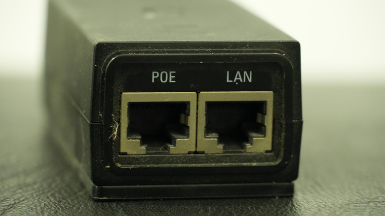 Close-up of a Power over Ethernet (PoE) injector showing two Ethernet ports labeled POE and LAN.