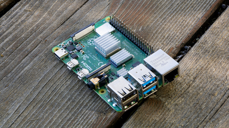 A Raspberry Pi naked computer board on a slatted wooden surface.