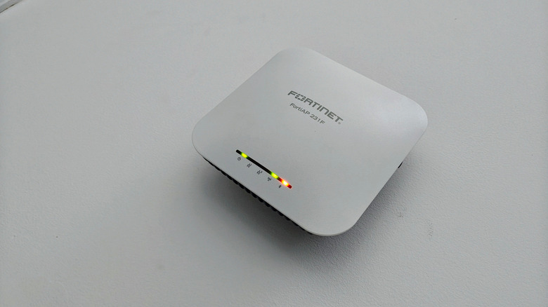A Fortinet Wi-Fi access point on an off-white surface.