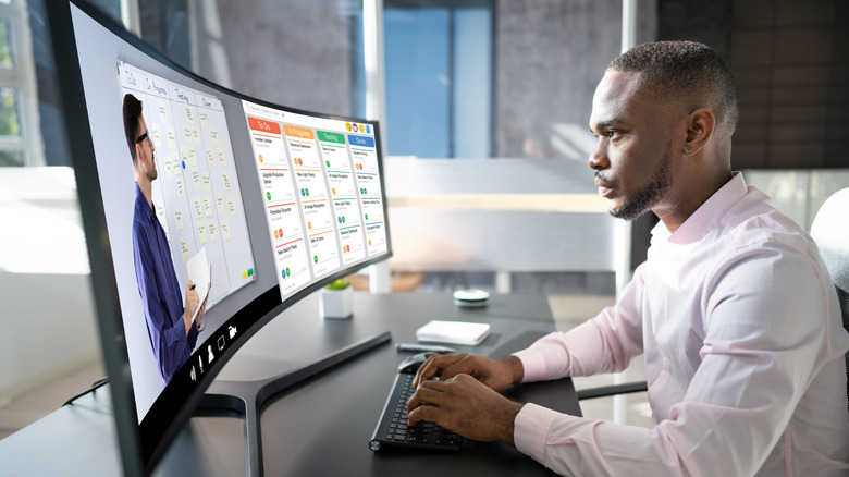 A man using two windows on an ultrawide monitor