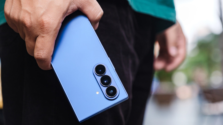 A person holding a book-style foldable phone at waist level