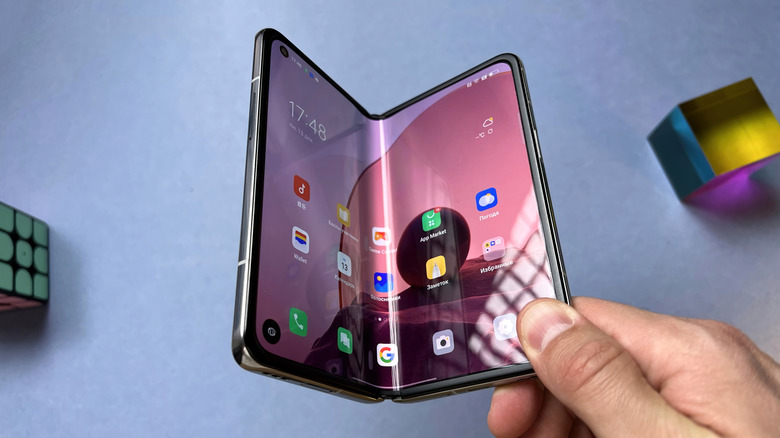 Holding a half-folded foldable phone, with light shining on its crease