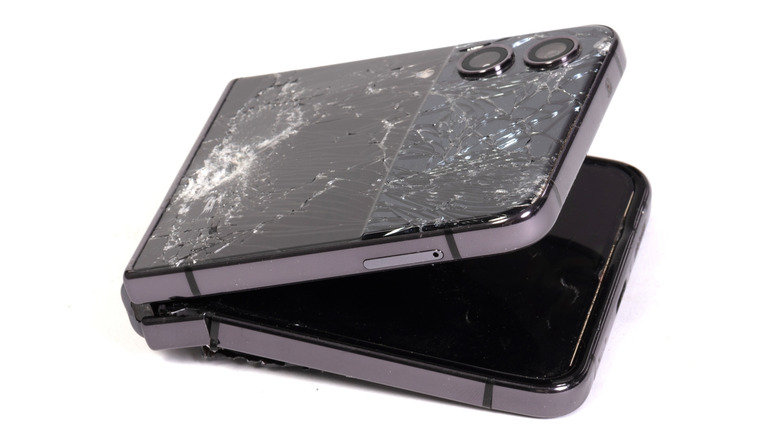 A broken clamshell folding phone on a white background