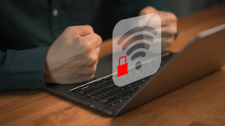 A person slams their fists on a laptop as a lock symbol next to a Wi-Fi symbol suggests that they are blocked from the network.