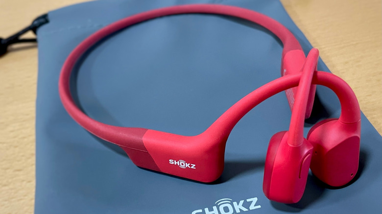 Red Shokz OpenRun earbuds on top of their carrying pouch