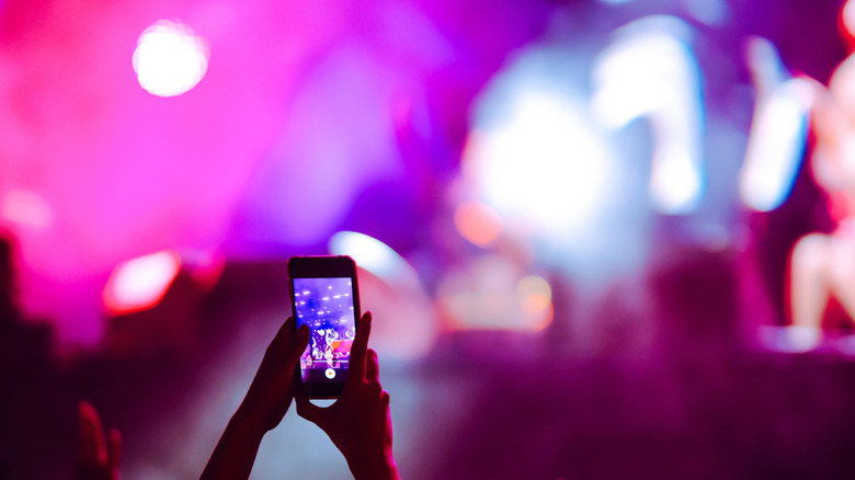 A person using their phone camera at a concert