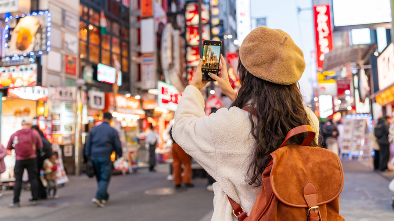 A person taking photos on a busy street with their phone