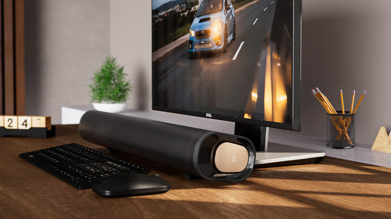 The Creative Stage Pro soundbar placed under a monitor next to a keyboard and mouse on a desk.