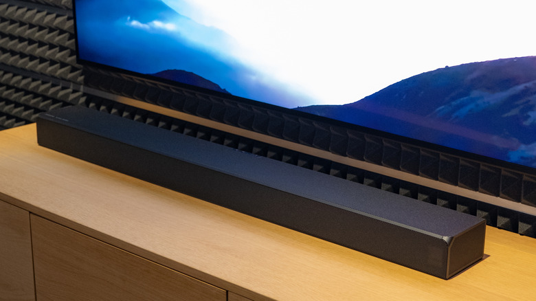 A soundbar on a TV unit next to a television in a soundproofed room.