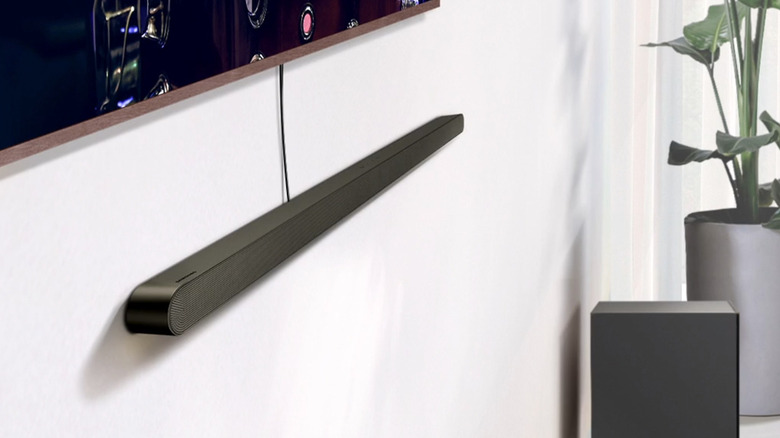 A black wall-mounted Samsung HW-S800D soundbar wired to a TV with the included subwoofer placed to the right.
