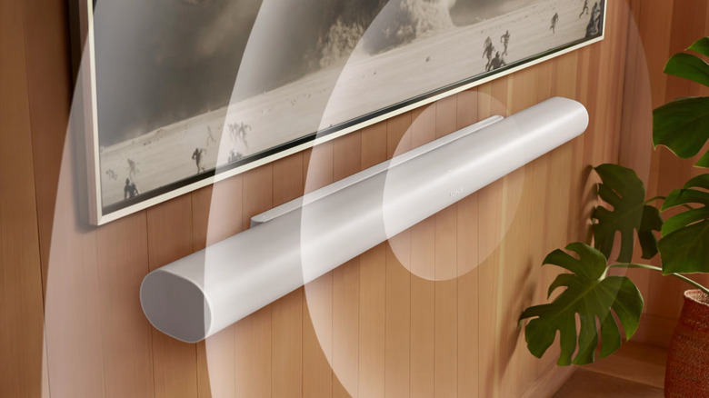 A white Sonos Arc Ultra soundbar mounted on a wooden wall, radiating circles to suggest audio playback.