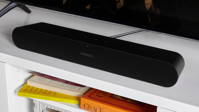The Sonos Ray placed on a white TV unit with some books on the shelf below it.