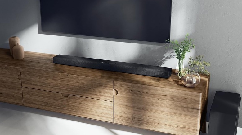 The Yamaha True X Bar 50A soundbar on a light brown TV unit with its subwoofer to the right.