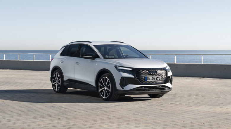 A silver Audi Q4 e-tron on a brick-laid surface near a waterfront