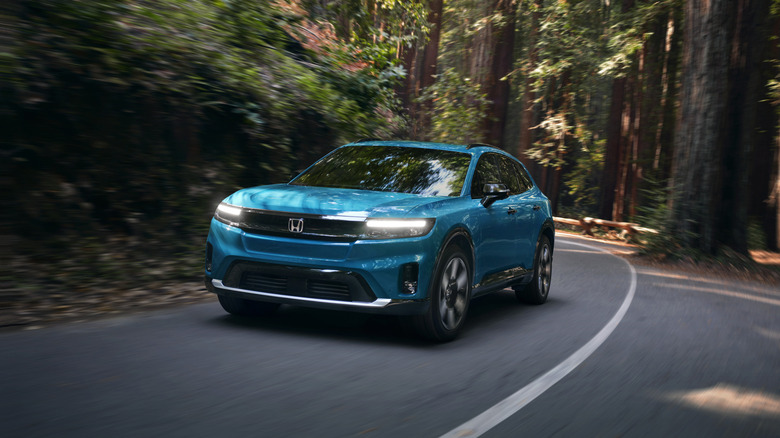 A blue Honda Prologue driving on a road in the forest