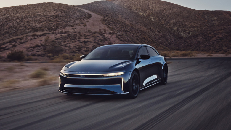 A black Lucid Air driving down a road in the desert