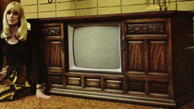A soman sitting next to a Cartrivision TV cabinet.