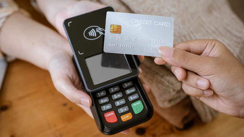 Person holding credit card over a card reader