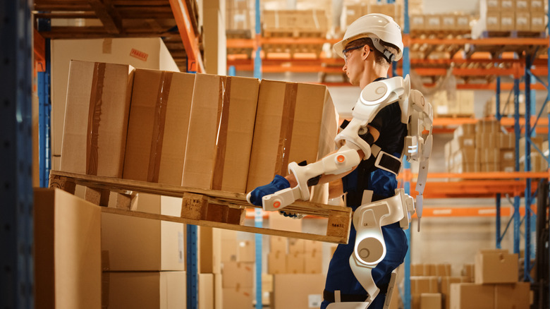 Person wearing exosuit carrying a pallet of boxes
