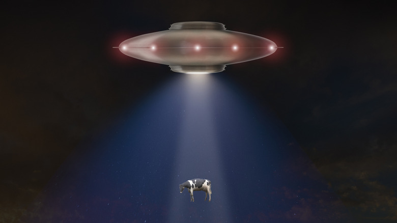 A spaceship beaming up a cow via tractor beam
