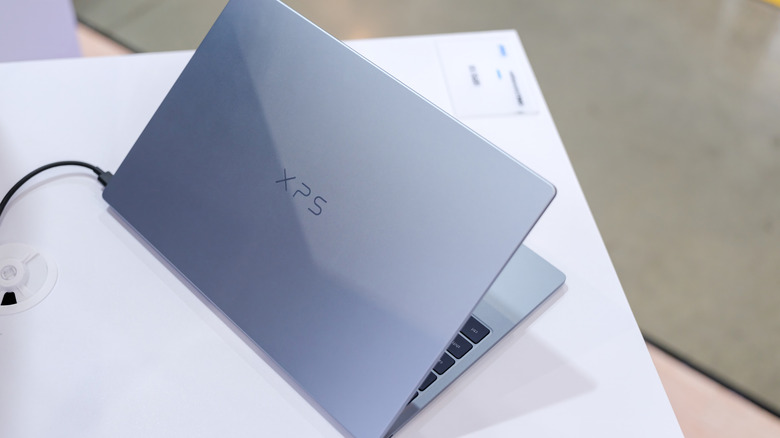 The back of a Dell XPS laptop, which is placed on a white surface.