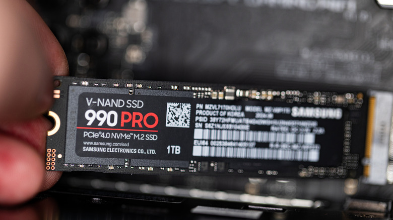 A hand installs a high-end Samsung NVMe SSD.